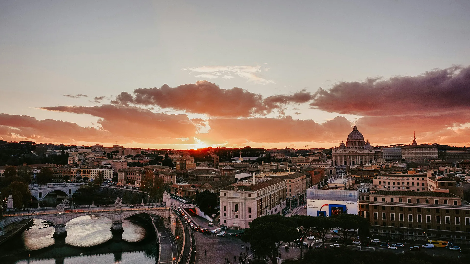 Sunset over Rome with St. Peter's Basilica and bridges crossing the Tiber River.